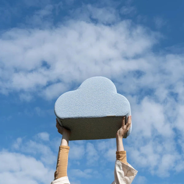 Person hebt das Present Stories Cloud Kissen in den Himmel – verspieltes Designkissen aus hochwertigem Schaumstoff mit textiler Oberfläche