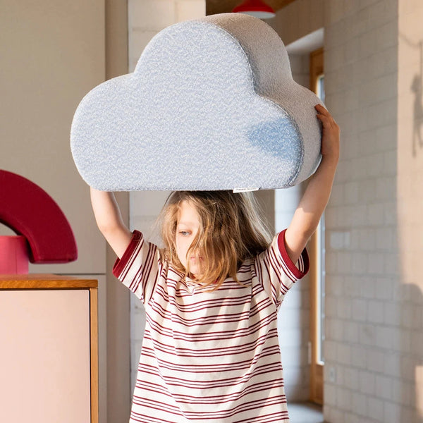 Ein Kind hebt das Cloud Kissen von Present Stories über den Kopf – multifunktionales Designobjekt für fantasievolles Spiel und modernes Kinderzimmer