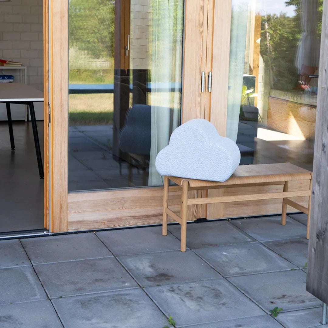 Cloud Kissen von Present Stories auf Holzbank – modernes Designobjekt aus Schaumstoff mit Möbelstoffbezug vor lichtdurchflutetem Architekturhaus