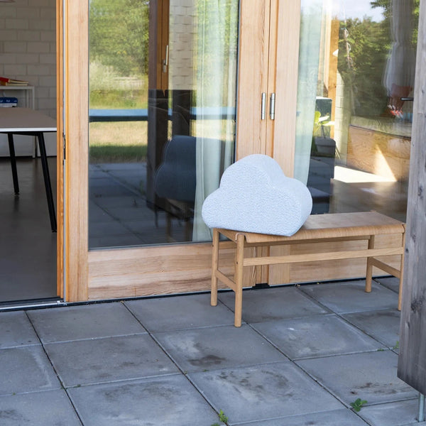 Cloud Kissen von Present Stories auf Holzbank – modernes Designobjekt aus Schaumstoff mit Möbelstoffbezug vor lichtdurchflutetem Architekturhaus