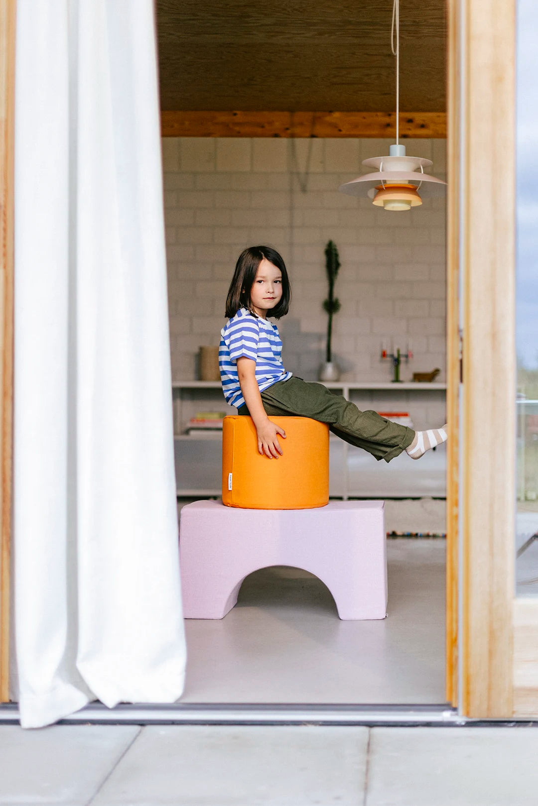 Kleines Kind lehnt sich an rosa Softwürfel von Present Stories – sichere, kreative Schaumstoffbausteine für aktive Kinder.