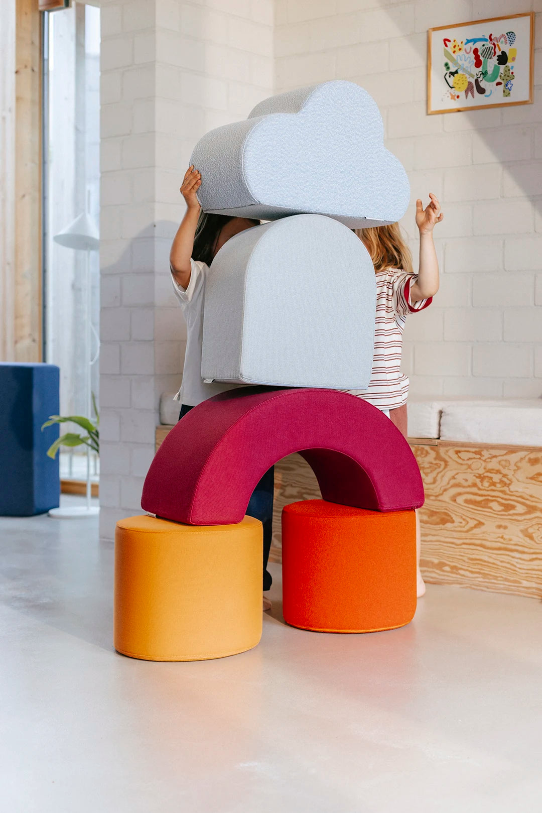 Zwei Kinder bauen fantasievoll mit bunten XXL Schaumstoffelementen des Remmi Demmi Ramba Sets und dem Cloud-Kissen von Present Stories
