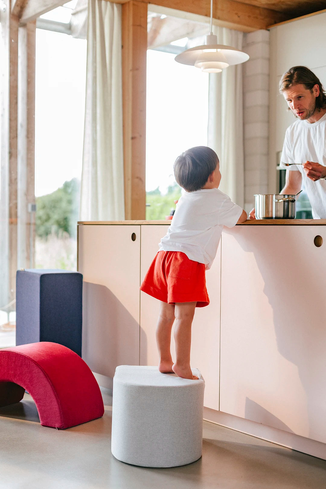 Kind steht auf einem Present Stories Softbaustein in Hockerform und nutzt ihn als Tritthilfe – multifunktionale XXL Schaumstoff Bausteine für Softplay, sicheres Spielen und praktische Anwendungen im Alltag.