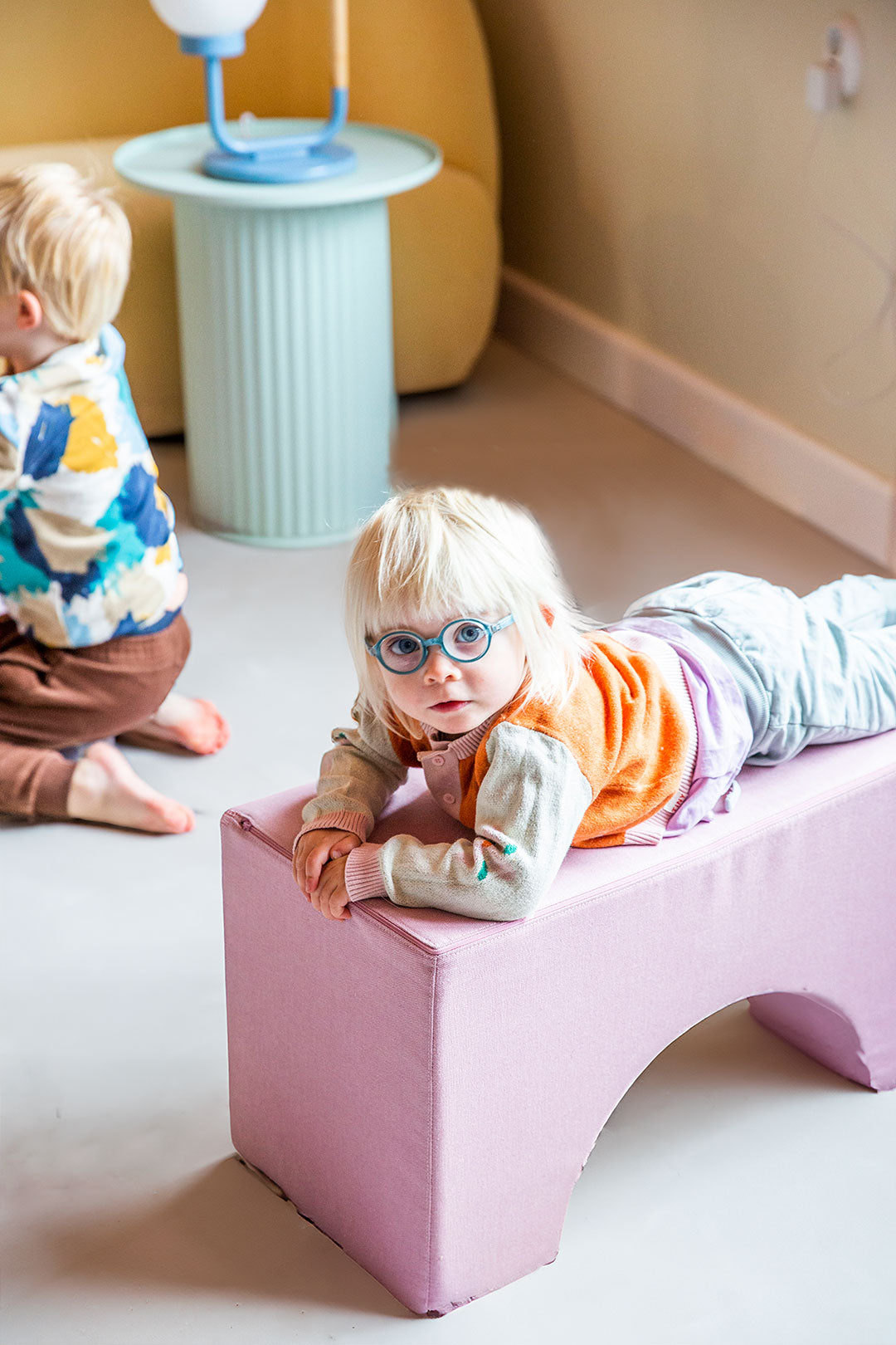 Kind liegt entspannt auf einem rosa Softbaustein von Present Stories – vielseitige Spielmöbel zum Klettern, Liegen und kreativen Spielen im Kinderzimmer.