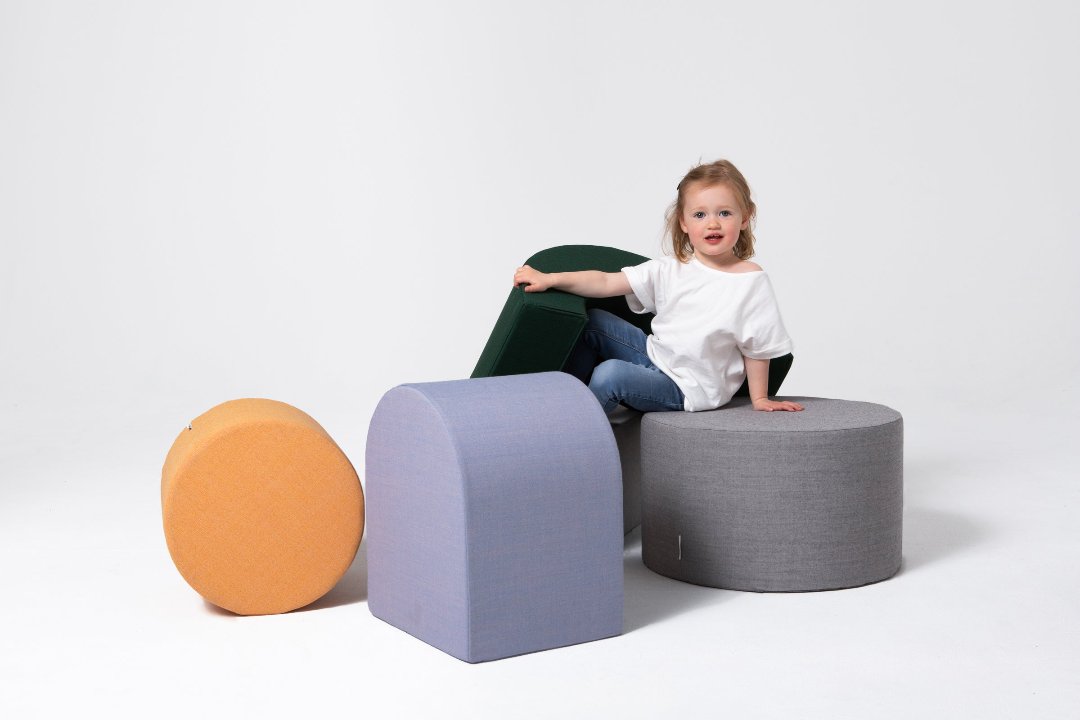 Kind sitzt und spielt mit bunten Softbausteinen von Present Stories – kreative Spielideen und multifunktionale Möbel fürs Kinderzimmer.