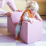 Kleinkind klettert spielerisch auf einem rosa Softbaustein von Present Stories – fördert Bewegung, Motorik und kreative Spielideen im Kinderzimmer.