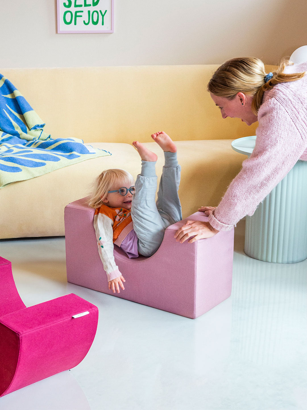 Kind lacht und spielt mit einem rosa Softbaustein von Present Stories – kreative Spielmomente, motorische Förderung und gemeinsame Familienzeit.