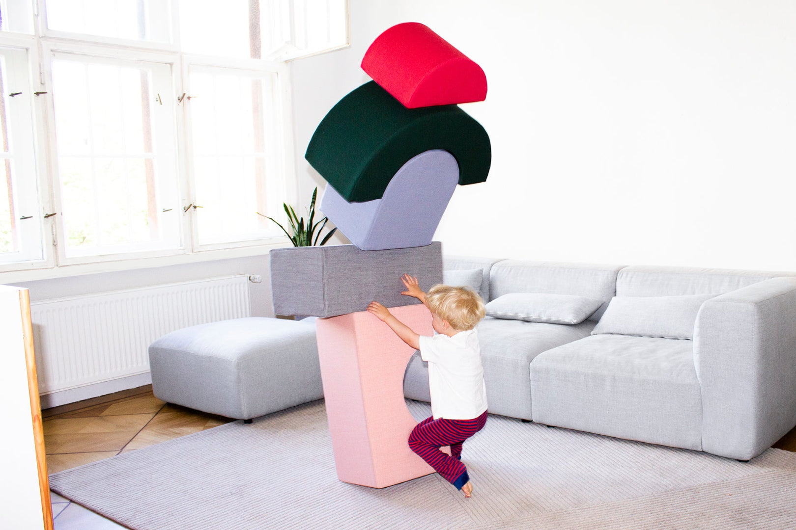 Kind stapelt große Softbausteine von Present Stories zu einem hohen Turm – fördert Kreativität, Gleichgewicht und motorische Fähigkeiten im Kinderzimmer.
